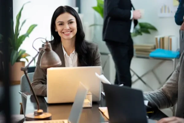 Working woman smiling sitting in her office in front of her laptop